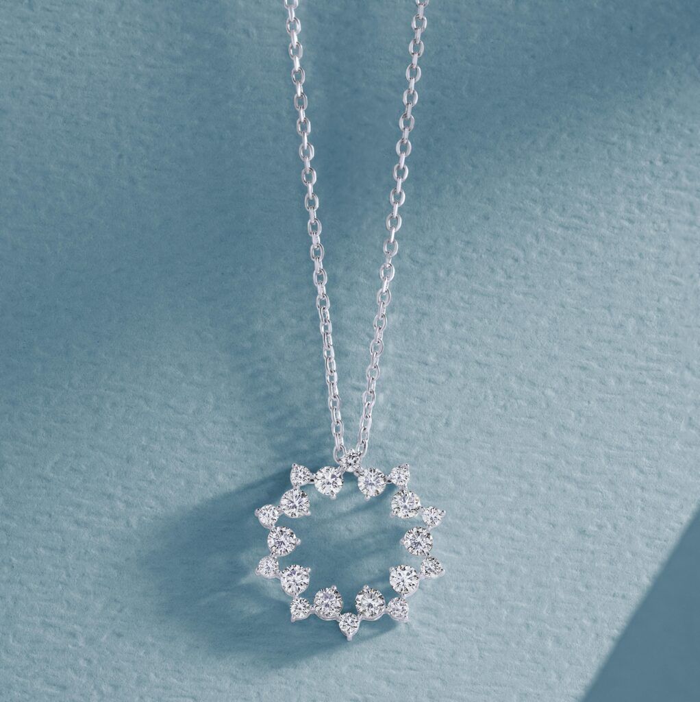 Close-up of a diamond pendant necklace on a textured blue background.